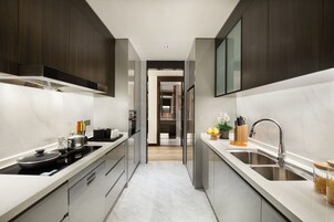 A modern kitchen with dark wood cabinets, a stainless steel sink, and a marble countertop.