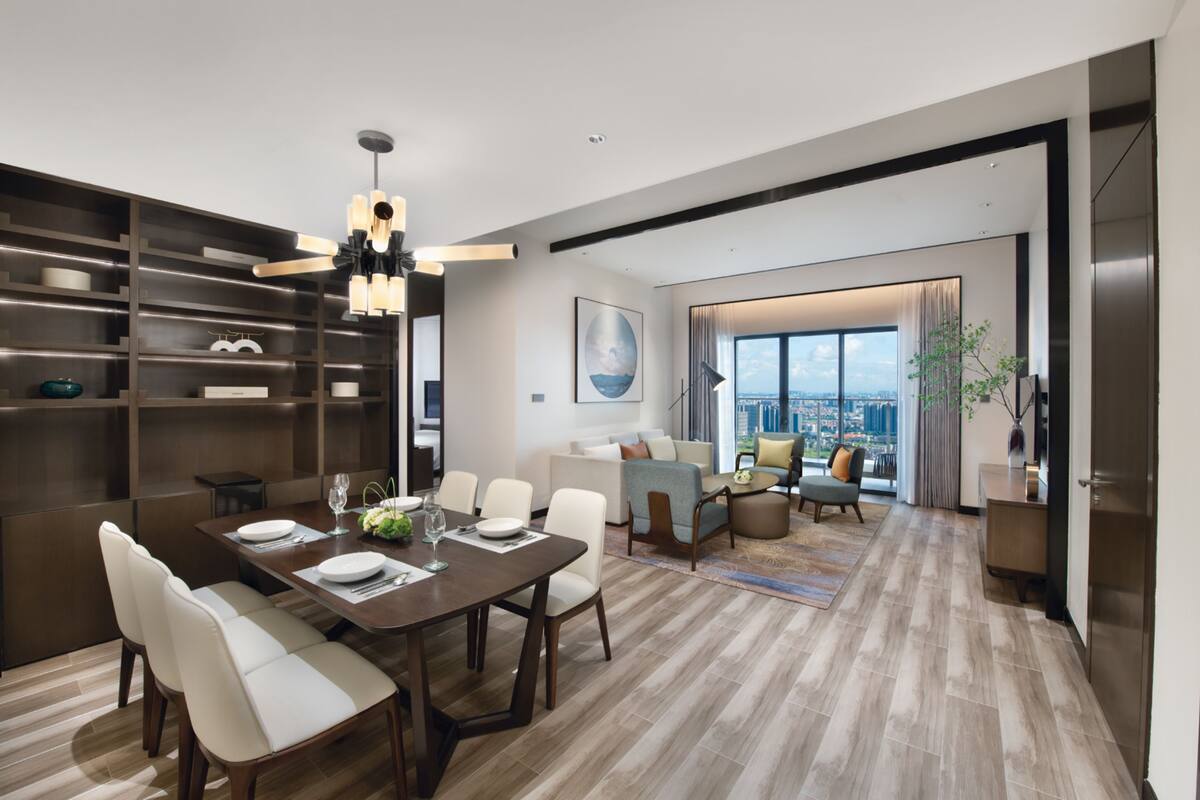 A modern living room with a dining area, large windows, and a city view.