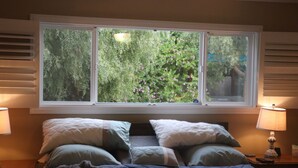 A bedroom with a large window, a bed with multiple pillows, and bedside lamps. - Casa Esperanza. Peaceful Get-away W/Hot Tub. (Salinas)
