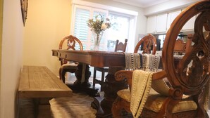 A dining area with a wooden table and chairs, a vase with flowers, and a window with blinds. - Casa Esperanza. Peaceful Get-away W/Hot Tub. (Salinas)