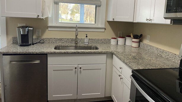 A kitchen with white cabinets, a granite countertop, a coffee maker, a sink, and a microwave. - Comfortable and Quiet 3 Bedroom Duplex (Nashville)