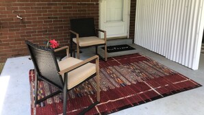 A small outdoor seating area with two chairs and a table, a red patterned rug, and a white door with a 'Welcome' mat. - Comfortable and Quiet 3 Bedroom Duplex (Nashville)