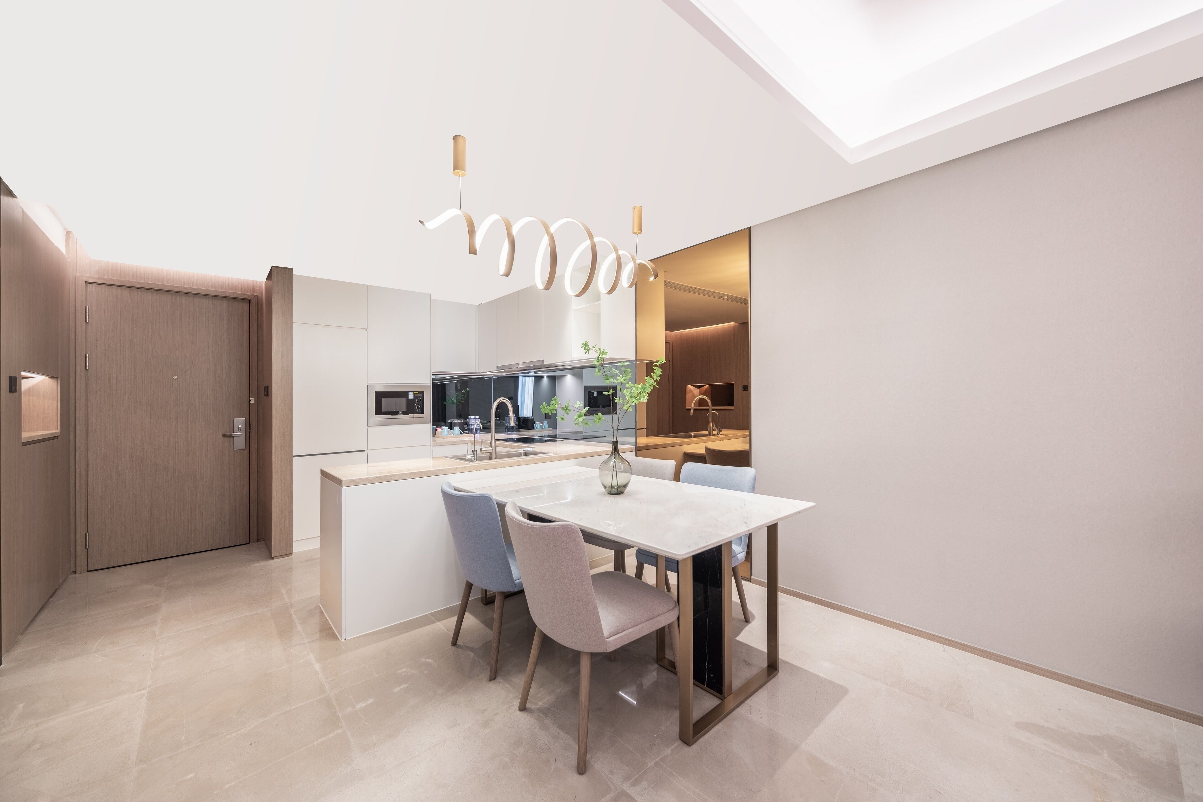 A modern kitchen with a central island, a dining area with a table and chairs, and a skylight above.
