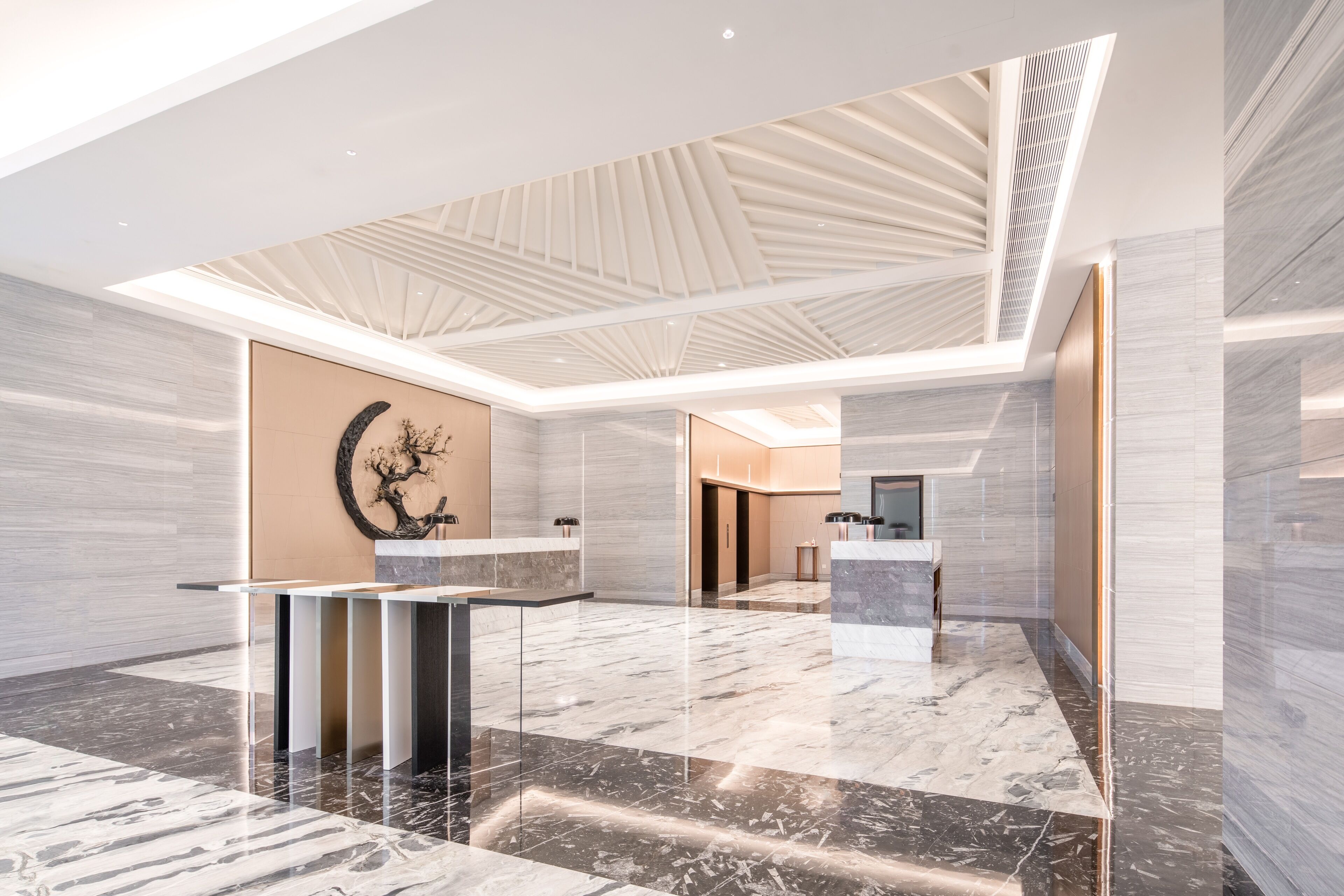 Een ruime lobby met een hoge plafond, marmeren vloeren en een centraal gelegen receptiebalie.
