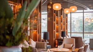 A modern interior with seating arrangements and a large window offering a view of greenery.