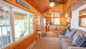 A cozy cabin interior with a wooden interior, a sofa, a dining table, and a kitchen area. - Lakefront, 5 min to Colgate, Sleeps 6, Kayaks (Hamilton)
