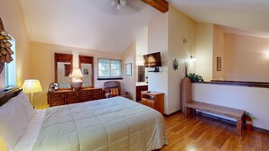 A bedroom with a bed, dresser, chair, TV, and a bench. - Pet Friendly | Close to Lifts | Fireplace | Charming | Angel Fire Chalet 52 (Angel Fire)
