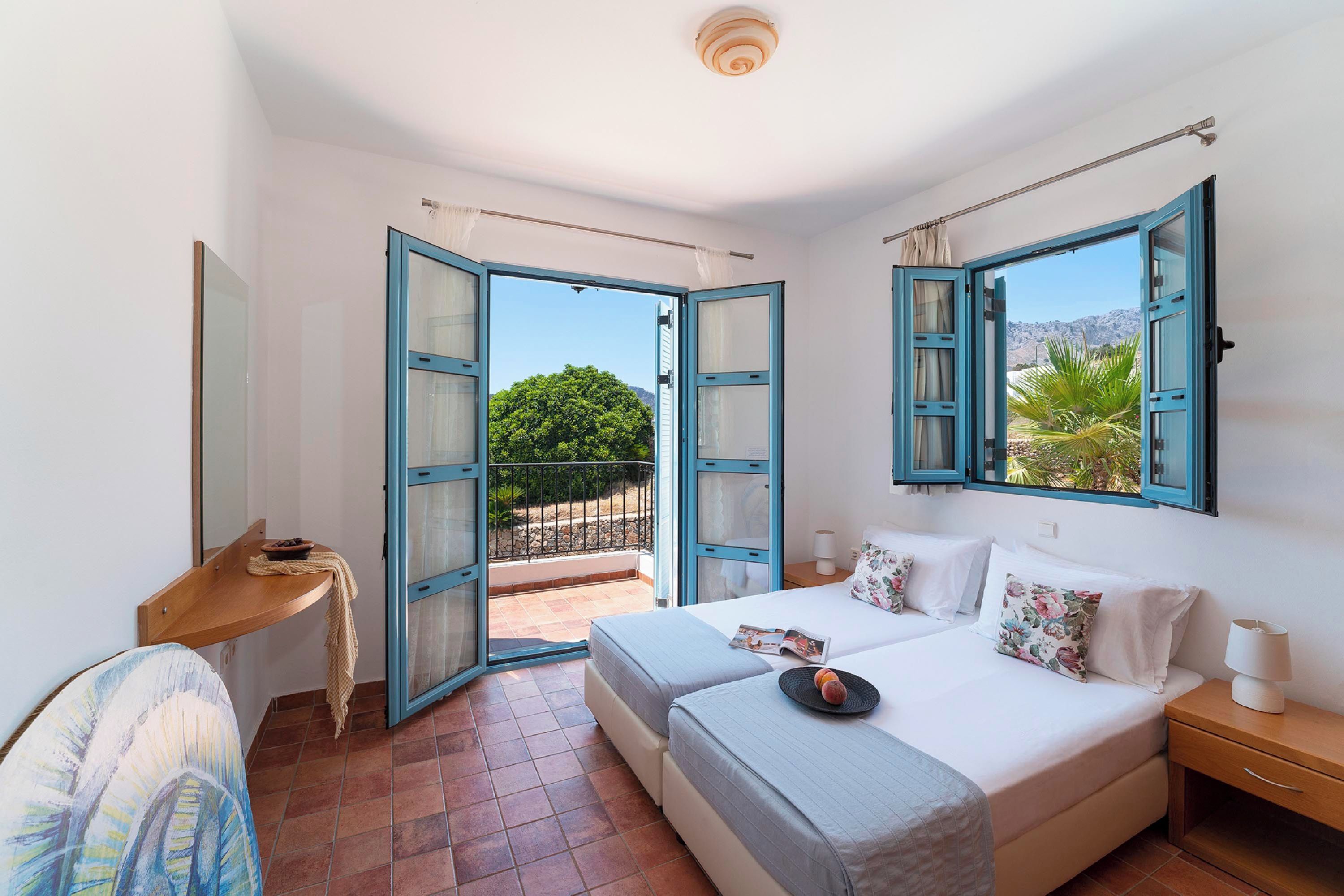 A bedroom with a bed, bedside tables, a desk, and a view of the outdoors.