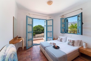 Un dormitorio con cama, mesitas de noche, un escritorio y vistas al exterior.