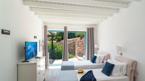 A bedroom with two beds, a TV, and a desk. - Villa Oceanis (Lindos)