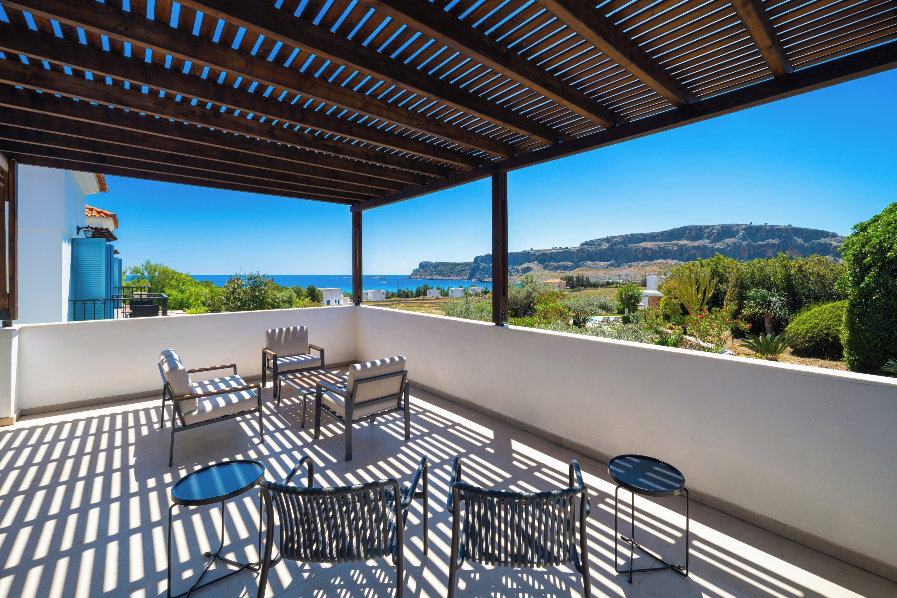 Un espacio de estar techado al aire libre con vista al mar y las colinas.