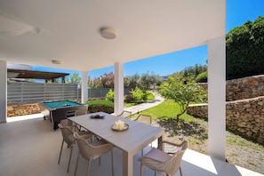 Un patio exterior con mesa de billar, sillas y una mesa de comedor.