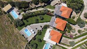 Une vue aérienne d’un quartier résidentiel composé de nombreuses maisons, chacune ayant un style de toit distinct et étant entourée de jardins bien entretenus.