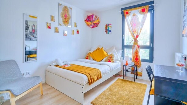 A modern bedroom with a bed, bedside table, chair, and artwork on the walls. - Chambres d'hôtes de Luxe Ma SuK (Saint-Denis)