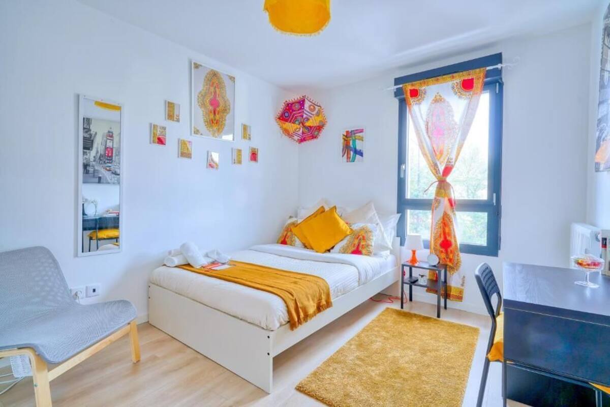 Une chambre à coucher moderne, avec un lit, une table de chevet, une chaise et des œuvres d’art accrochées aux murs.