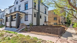 Une maison moderne à deux étages, dotée d’un porche abrité, d’un jardin aménagé et d’un bâtiment en briques attenant.