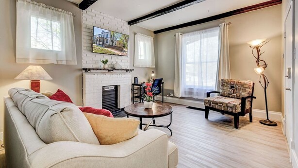 Un salon avec une cheminée, un canapé, une table basse et un fauteuil à motifs.