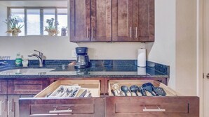 Una cucina con mobili in legno, un piano di lavoro in granito, una moka e un espositore per piatti.