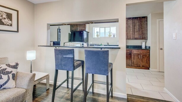 Una cucina moderna con angolo bar, mobili in legno e zona pranzo con una sedia e una lampada.