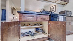 Una cucina compatta con mobili in legno, un forno a microonde e diversi utensili da cucina.