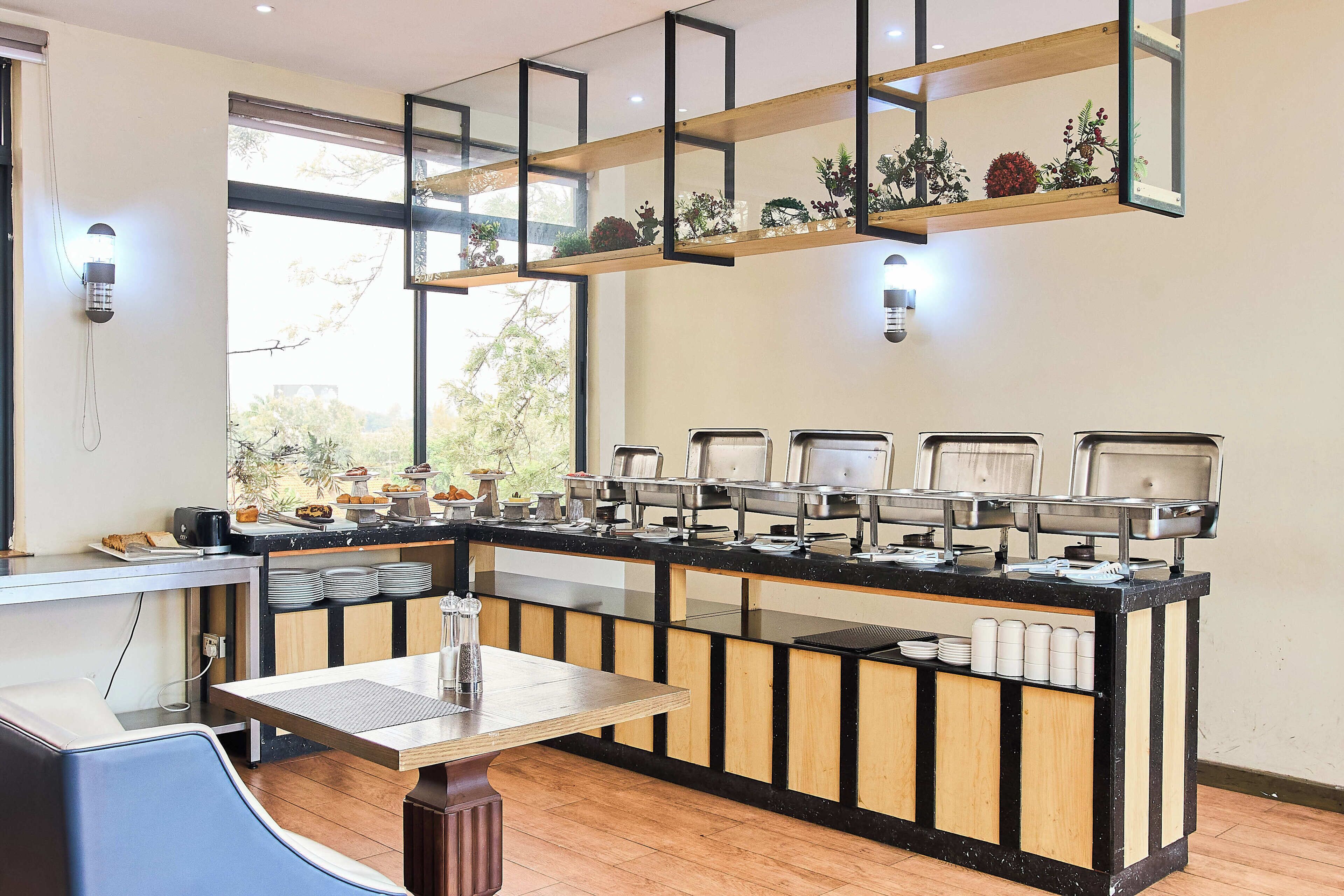 A breakfast bar with a variety of food items and a seating area with a table and chairs.