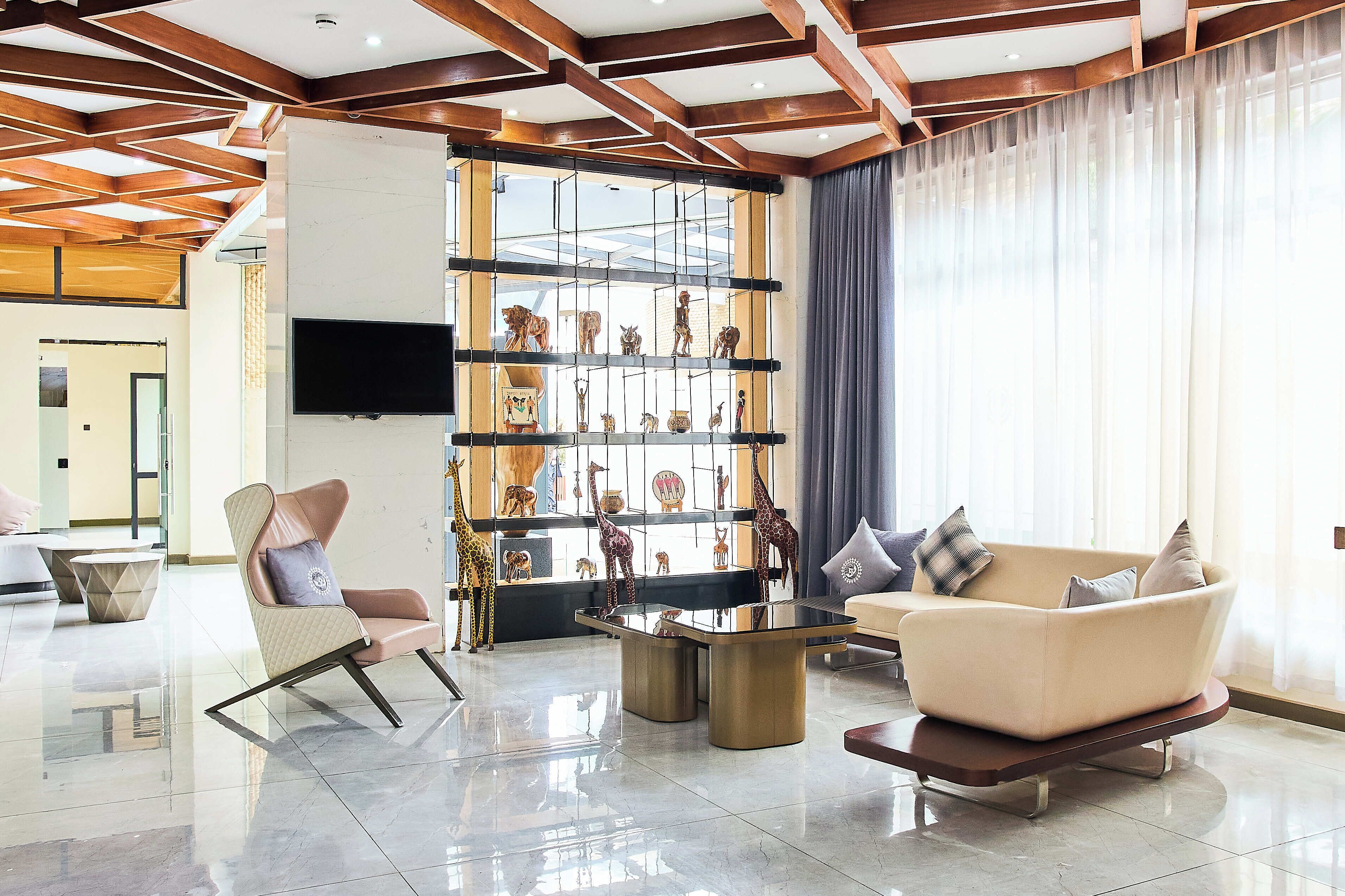 Un salon moderne avec un canapé, des fauteuils, une table basse et un téléviseur fixé au mur.