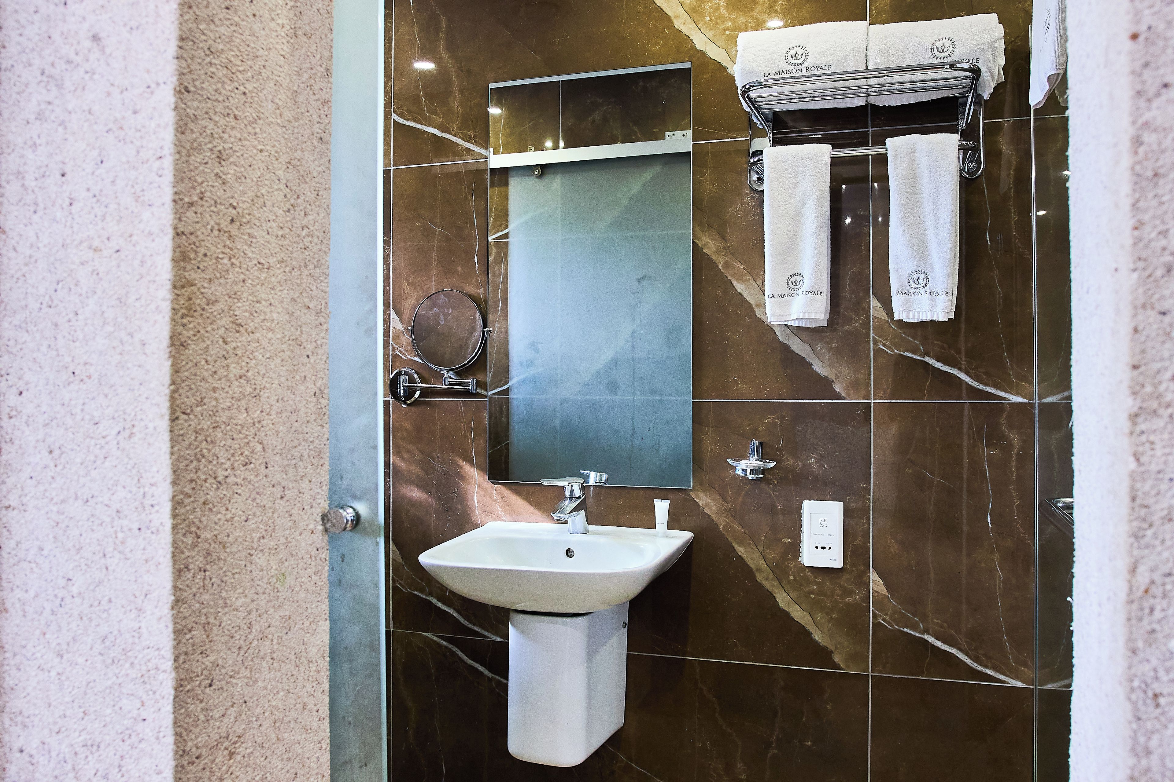 A bathroom with a white sink, a mirror, and a towel rack with two towels.