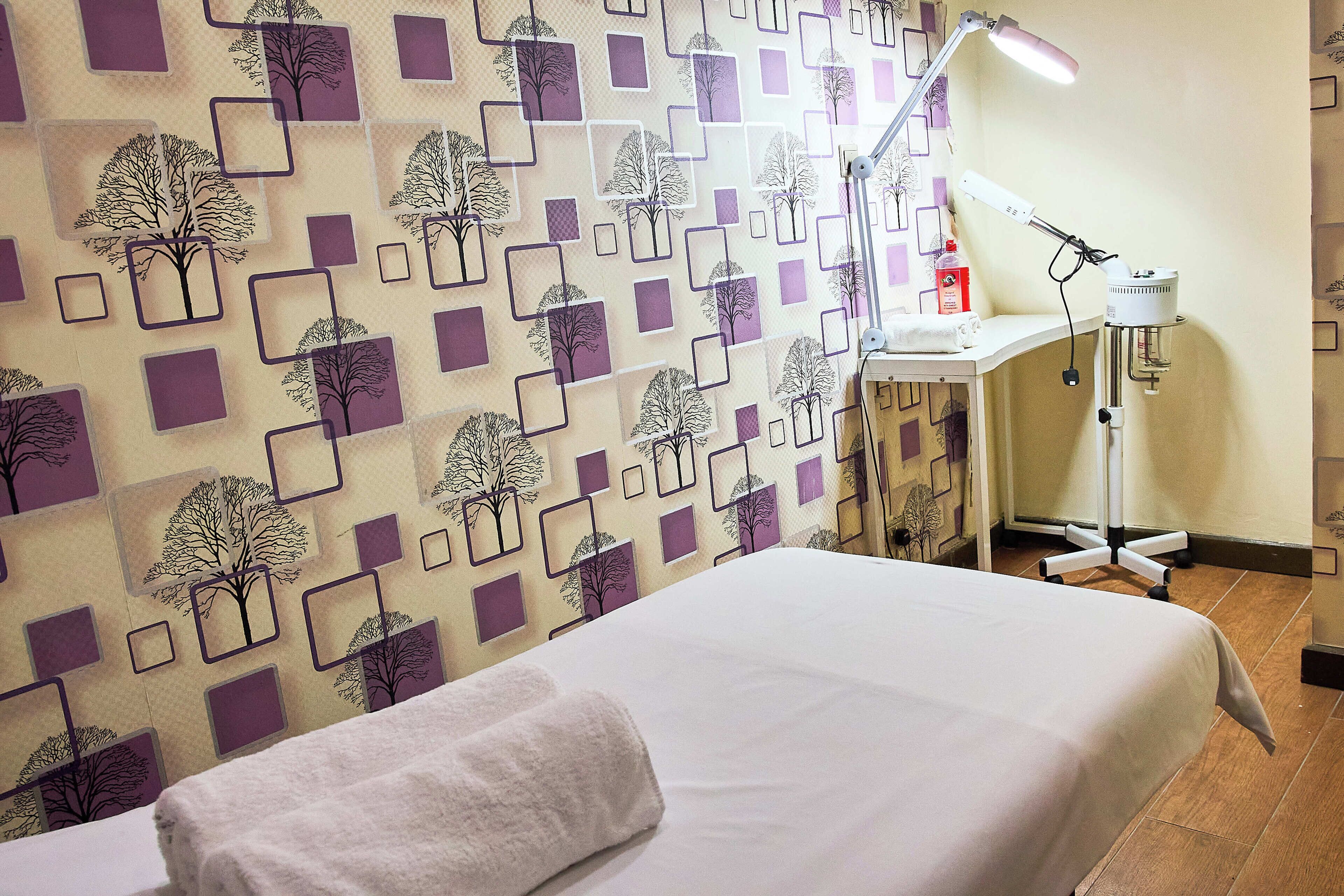 A room with a bed, a desk, a chair, a lamp, and a wall with a geometric pattern.