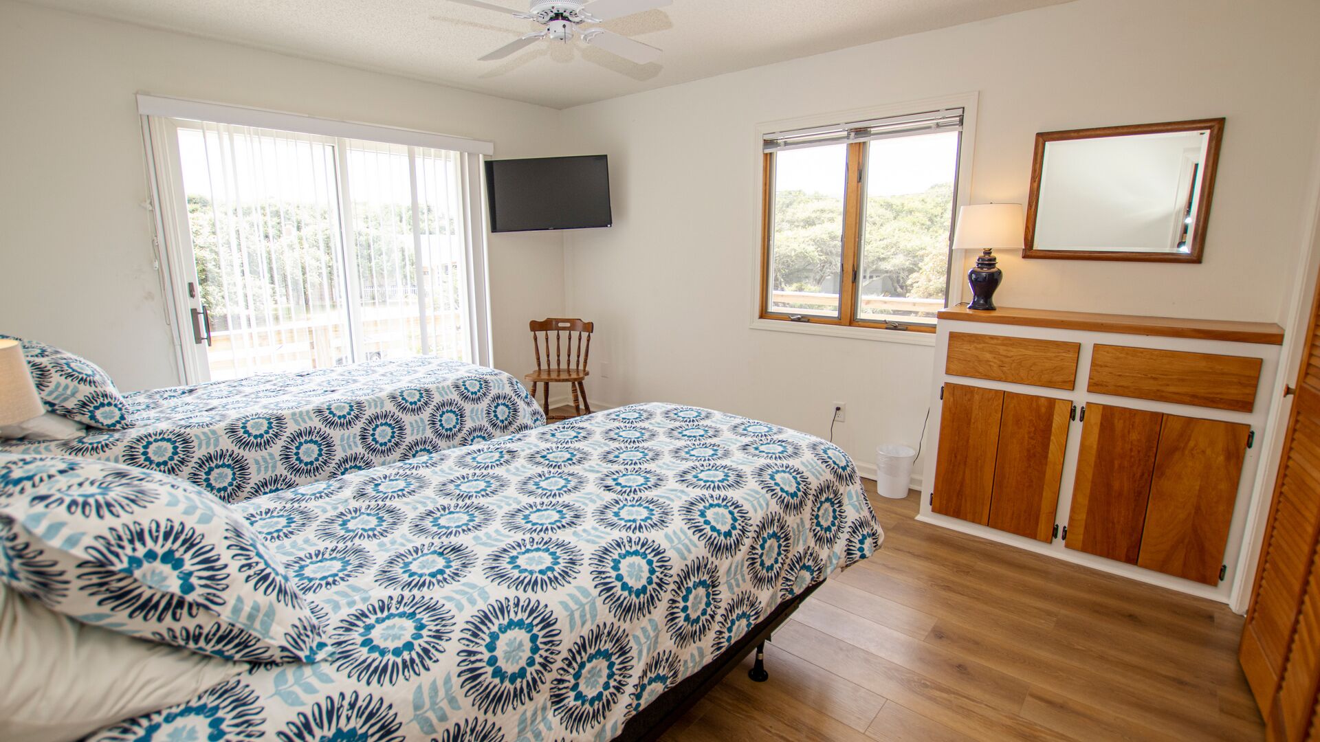 A bedroom with a bed, a chair, a TV, a window, and a cabinet.