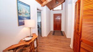 Ein Flur mit Holzboden, einem Holztisch mit einer weißen Lampe, einem Poster an der Wand und einer Holztür.