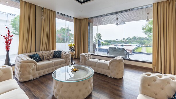 Ein geräumiges Wohnzimmer mit einem großen Fenster, einer Sofagarnitur und einem Glastisch.