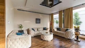 Ein modernes Wohnzimmer mit einem Ecksofa, einem runden Couchtisch und einem großen Fenster mit Vorhängen.