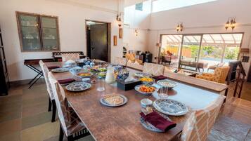 A dining area with a long table set for a meal, surrounded by chairs.