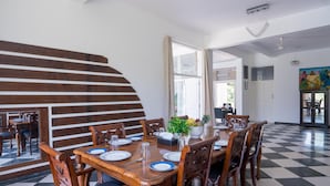 A dining area with a wooden table set for six, surrounded by chairs. There is a staircase with wooden steps leading to an upper level.