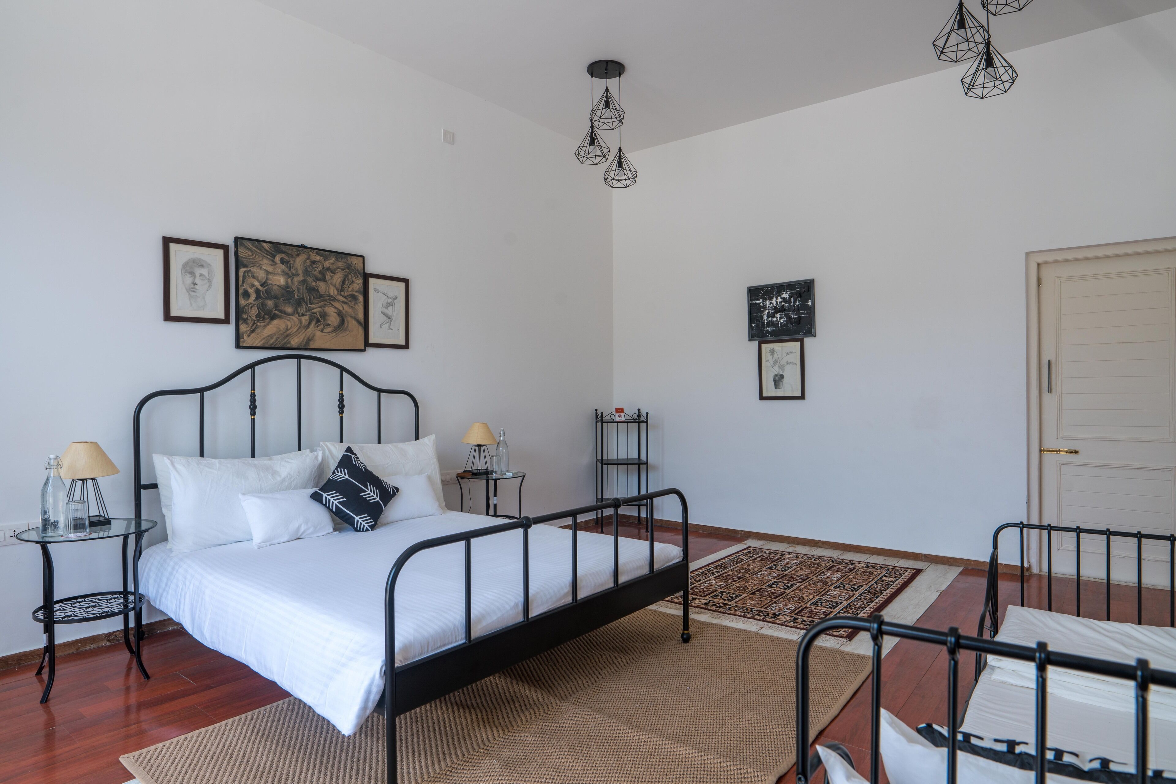 Quarto bem arrumado com cama, mesas de cabeceira e obras de arte nas paredes.