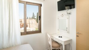 A small, bright room with a window, a white desk, a mirror, and a TV mounted on the wall. - Stefania Villa Ena in Roumeli (Mylopotamos)