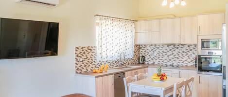 Cocina compacta con comedor, horno empotrado y un televisor de pantalla plana en la pared.