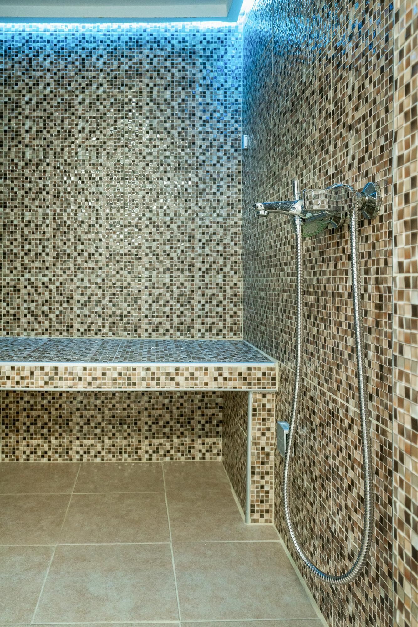 A shower area with a bench, tiled walls, and a showerhead.