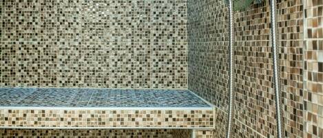 A shower area with a bench, tiled walls, and a showerhead.