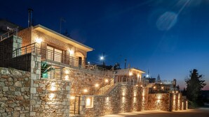 Un bâtiment en pierre doté de nombreux balcons et d’escaliers, illuminé par des éclairages extérieurs.