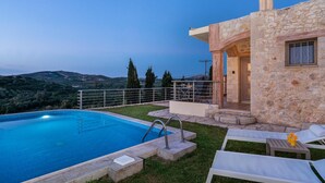 Une villa en pierre dotée d’une piscine, d’un espace salon extérieur et offrant une vue sur les collines.