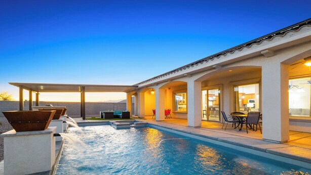 Ein Swimmingpool mit einer Terrasse, Sitzgelegenheiten im Freien und Blick auf den Sonnenuntergang.