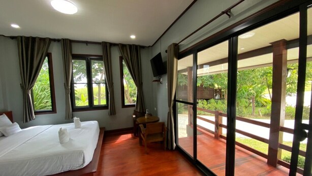 A hotel room with two beds, a TV, and a balcony with a wooden railing. - Pruksa View Homestay (Nam Nao)