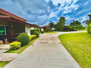 A pathway leading to a row of single-story buildings with a covered outdoor seating area on the left. - Pruksa View Homestay (Nam Nao)