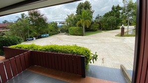 A view from a balcony overlooking a parking area with a garden and trees. - Pruksa View Homestay (Nam Nao)