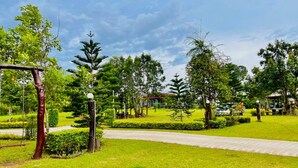 A well-maintained garden with a paved walkway, various trees, and a gazebo. - Pruksa View Homestay (Nam Nao)
