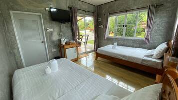 Habitación de hotel con dos camas, televisión, refrigerador pequeño y ventana con cortinas.