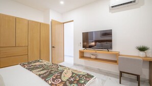 Ein Schlafzimmer mit Bett, Fernseher, Schreibtisch und Klimaanlage.