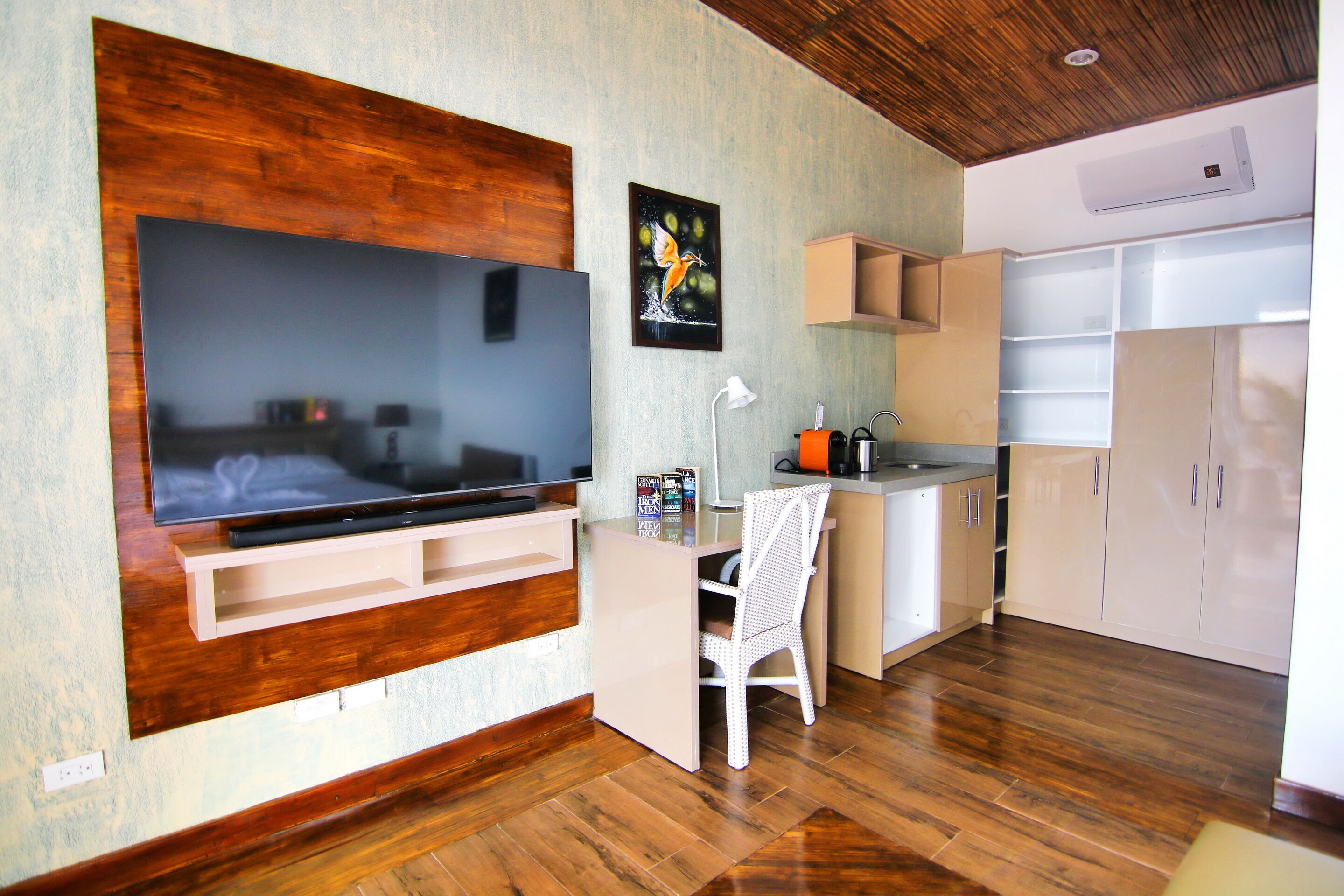 A modern kitchen with wooden flooring, a built-in TV, and white cabinetry.