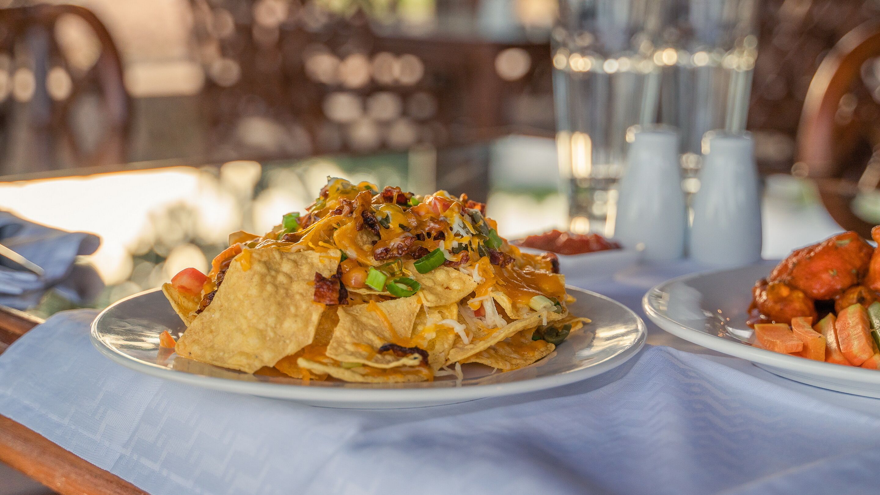 Um prato de nachos com queijo, bacon e cebolinha.